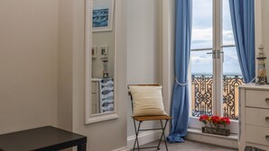 A room with a view of the sea, a chair, a small table, and a dresser. - The Old Spy Headquarters (Folkestone)