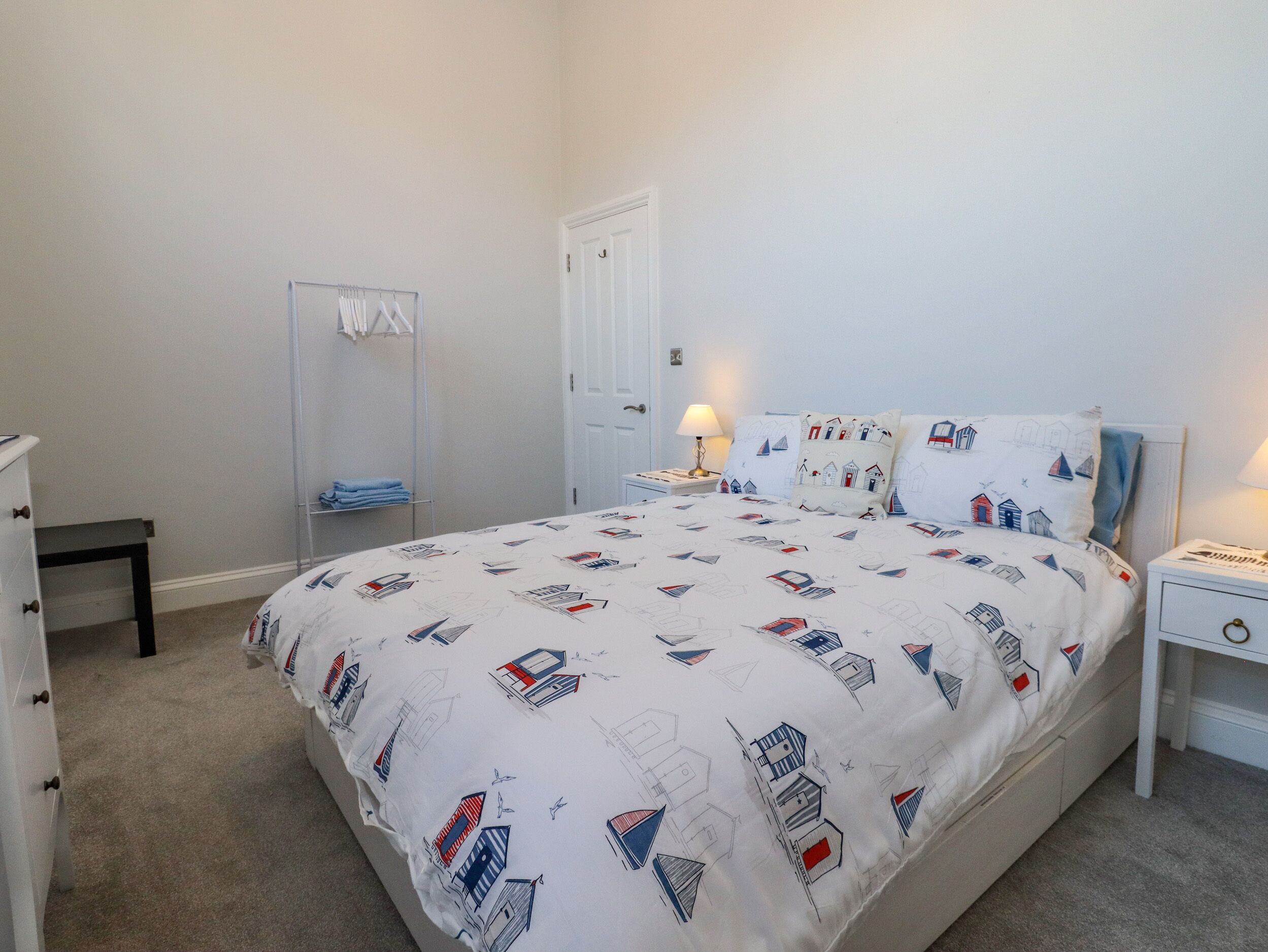 A bedroom with a bed, a bedside table, a lamp, a wardrobe, and a mirror.