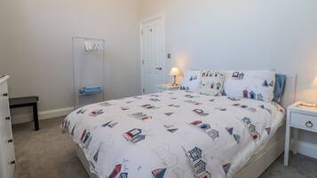 A bedroom with a bed, a bedside table, a lamp, a wardrobe, and a mirror.