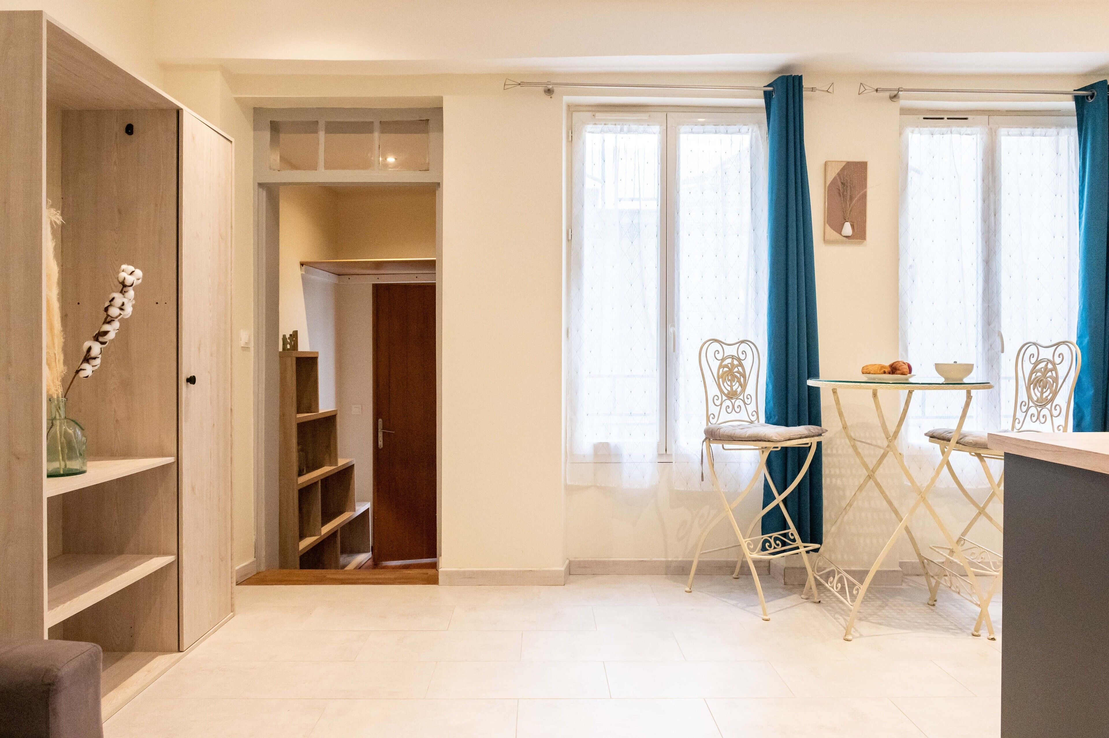 A modern kitchen with white cabinets, a wooden door, and a dining area with a table and chairs.