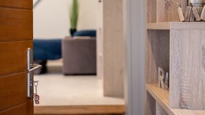A wooden door with a keychain, a blurred room interior with a bed and a plant, and a shelf with wooden objects and a candle.