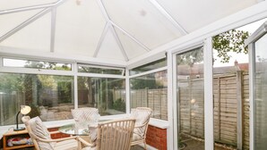 A conservatory with a glass door, a table, and two wicker chairs. - 2 Bathsheba Terrace (Dorchester)