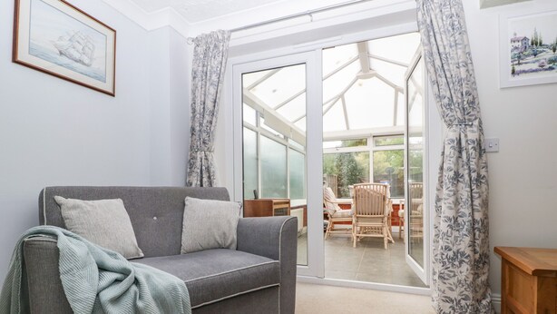 A cozy living room with a grey sofa, a green throw blanket, and a dining area with wicker chairs. - 2 Bathsheba Terrace (Dorchester)