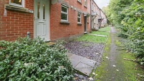 A row of red brick houses with white doors and windows, a narrow pathway, and lush greenery. - 2 Bathsheba Terrace (Dorchester)