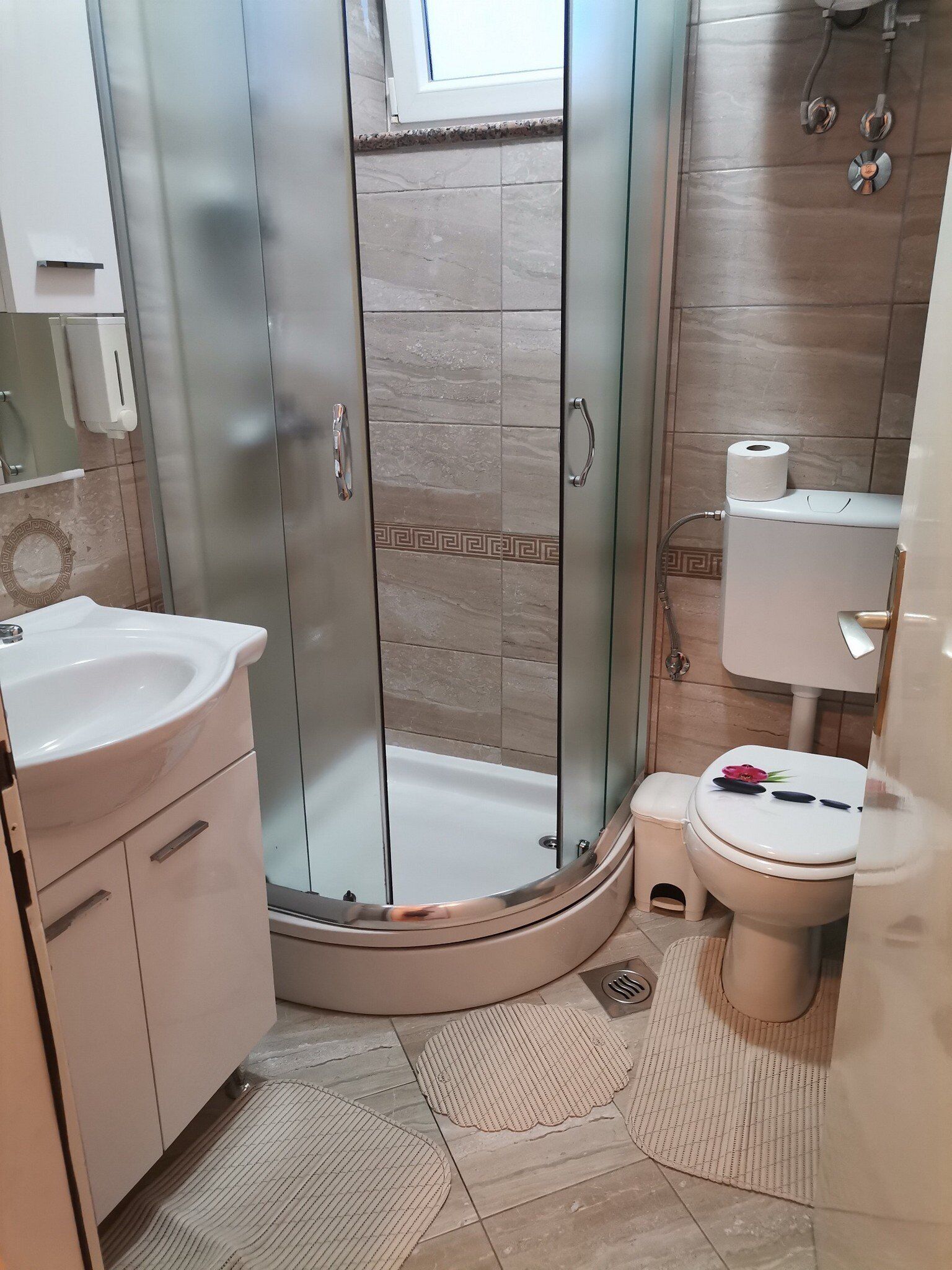 Kylpyhuone, jossa on lasiseinällä varustettu suihku, wc ja pesuallas.