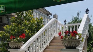 Una escalera con barandillas blancas, escalones color beige y macetas con flores rojas en la parte superior e inferior.