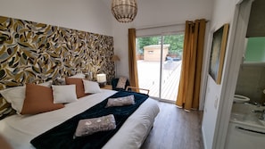 A hotel room with a large bed, a patterned wall, a view of the outside, and a bathroom. - Very bright Scandinavian chalet located 3 min. from the lake and 10 min. of the (BISCARROSSE)