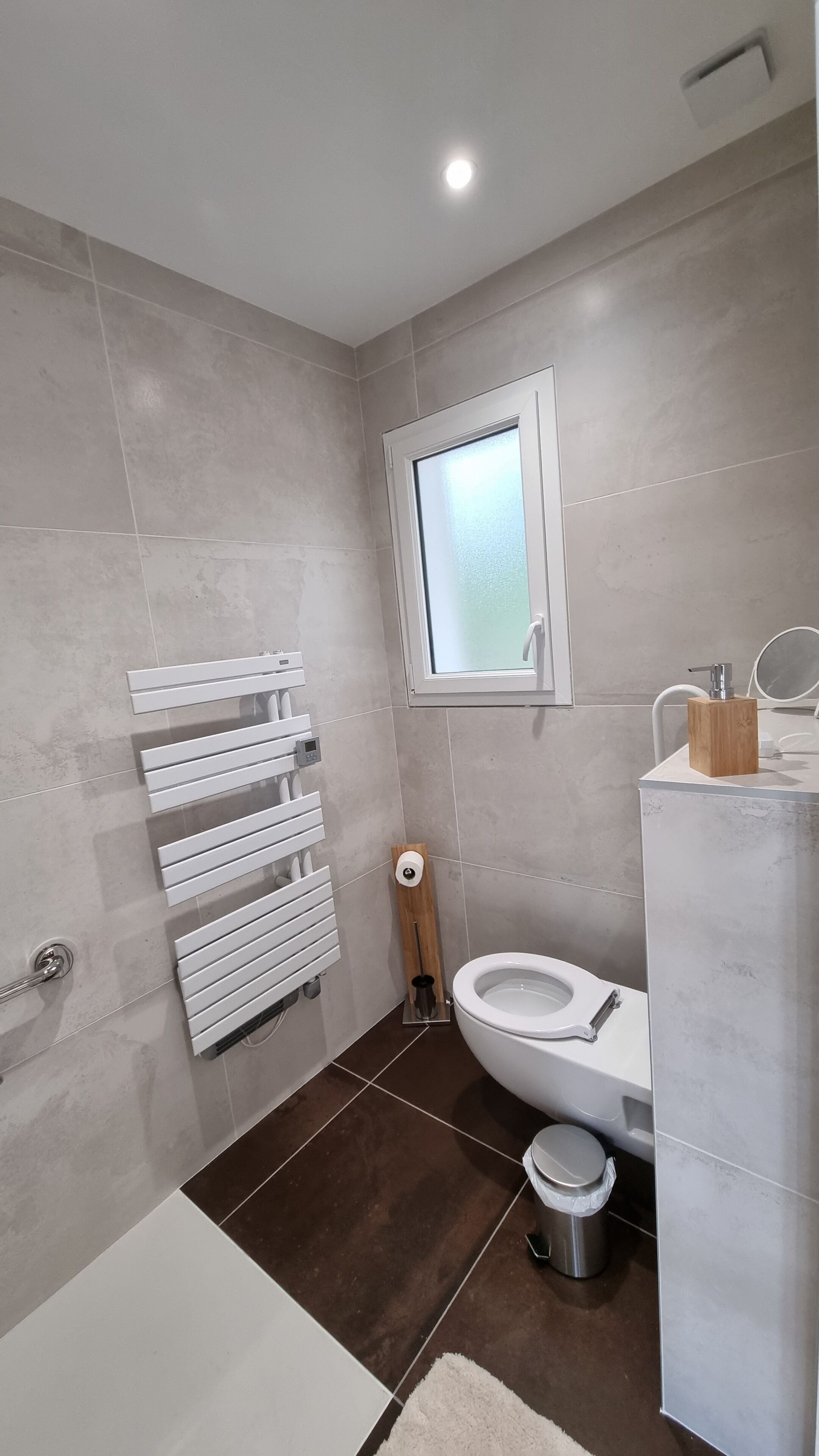 A modern bathroom with a toilet, bidet, and a window.