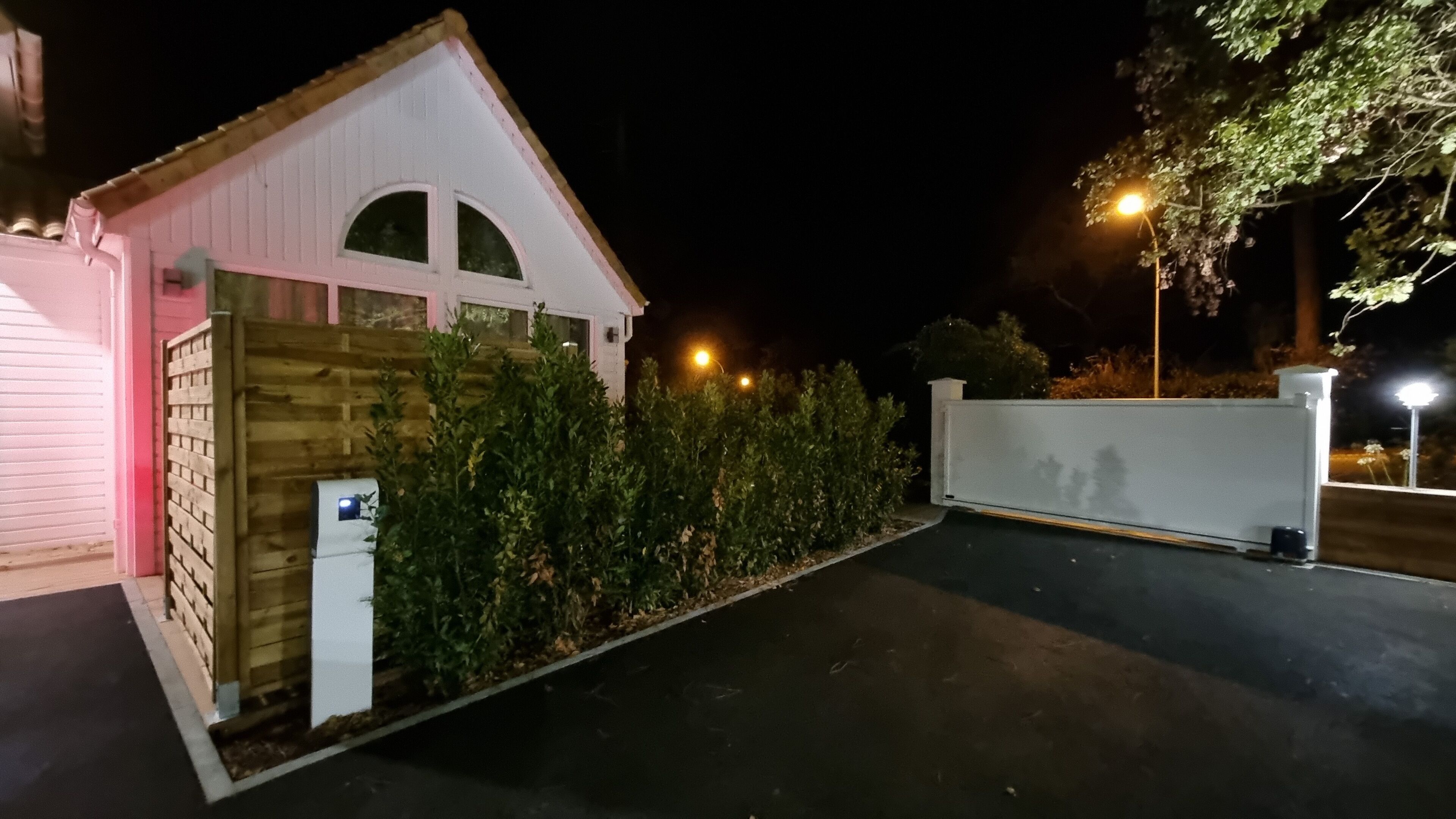 A small, single-story building with a sloped roof and a wooden fence.