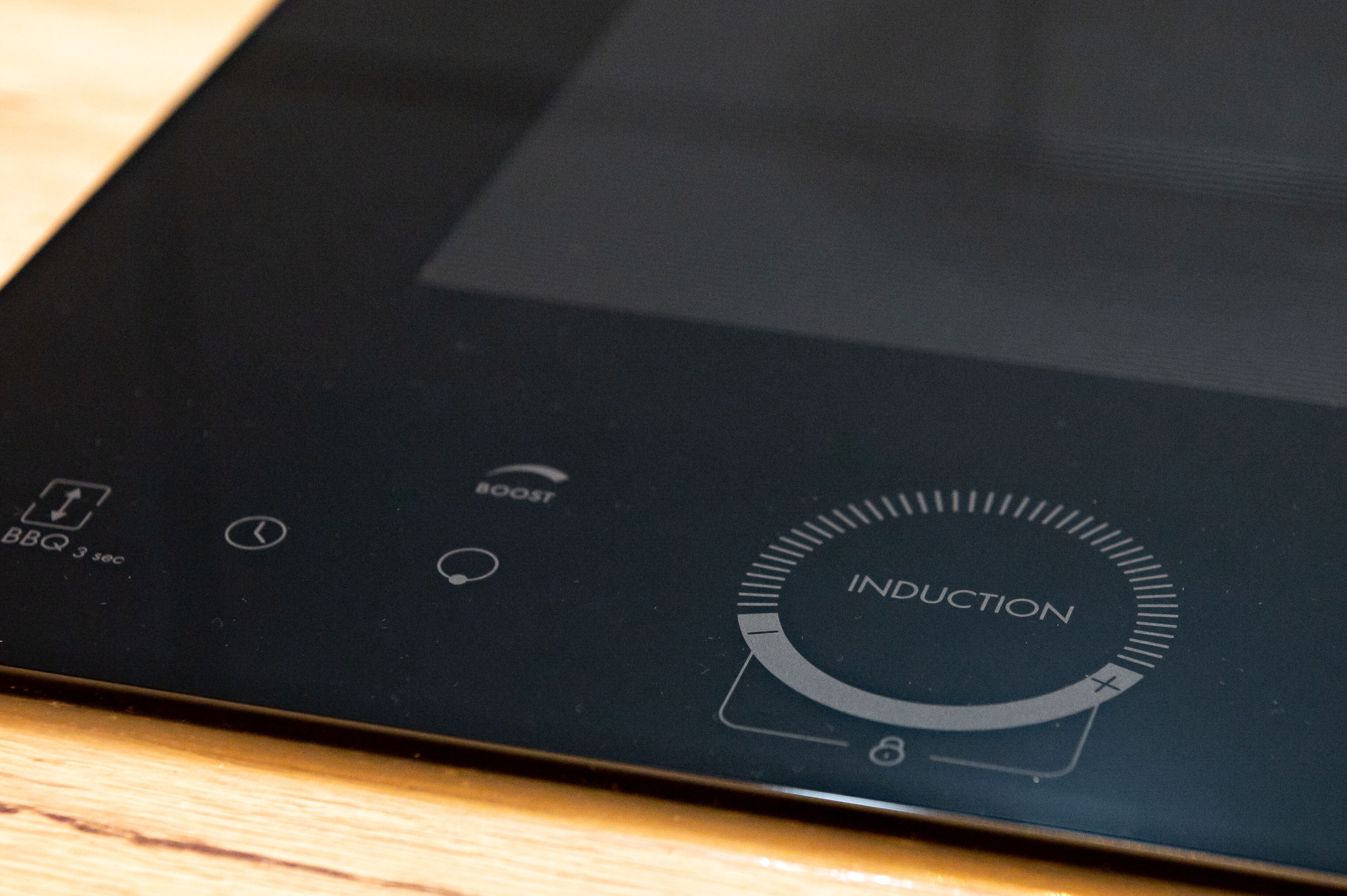 A close-up of a black induction cooktop with a digital display and control buttons.