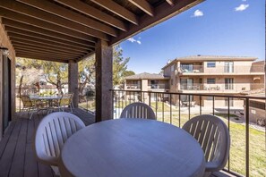 Un espace extérieur abrité, équipé d’une table et de chaises, donnant sur un immeuble d’habitation.