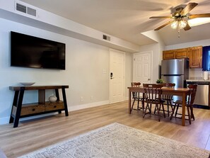 Una cocina moderna con armarios de madera, un refrigerador de acero inoxidable y un comedor con mesa y sillas.