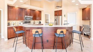 A modern kitchen with wooden cabinets, stainless steel appliances, and a central island with bar stools.