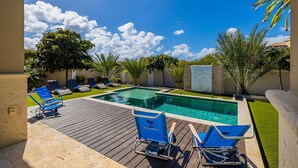 A swimming pool with blue lounge chairs and a wooden deck.