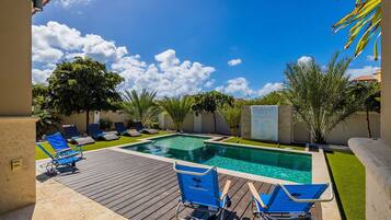 A swimming pool with blue lounge chairs and a wooden deck.