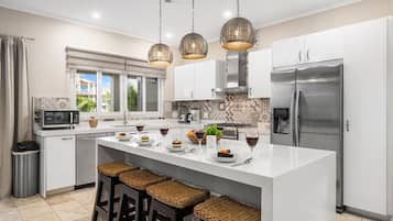 A modern kitchen with white cabinetry, a stainless steel refrigerator, and a central island with bar stools.