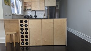 A modern kitchen with wooden cabinets, a stainless steel refrigerator, a coffee maker, and a sink.