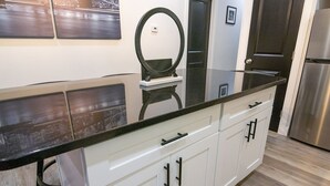 Eine Küche mit schwarzer Arbeitsplatte, weißen Schränken und einem Edelstahl-Kühlschrank.