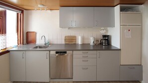 Eine moderne Küche mit grauen Schränken, einem Edelstahl-Geschirrspüler, einer Kaffeemaschine und einem Kühlschrank.