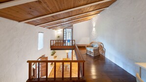 Un loft spazioso con travi in legno, un'area pranzo e una sedia in vimini.