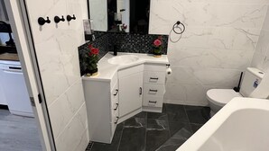 A modern bathroom with a white vanity, black tiled backsplash, a large mirror, a toilet, and a bathtub. - Newly Listed and Centrally located , walk to restaurant's , cafes and shopping , (Boondall)