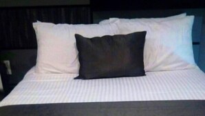 A bed with white bedding and a black pillow. - CONDOS DR (Acapulco)