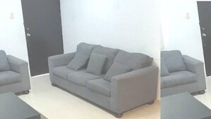 A grey sofa with wheels in a room with a tiled floor and a black door. - CONDOS DR (Acapulco)