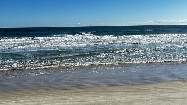 Een strand met golven en een heldere lucht.