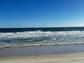 A beach with waves and a clear sky.