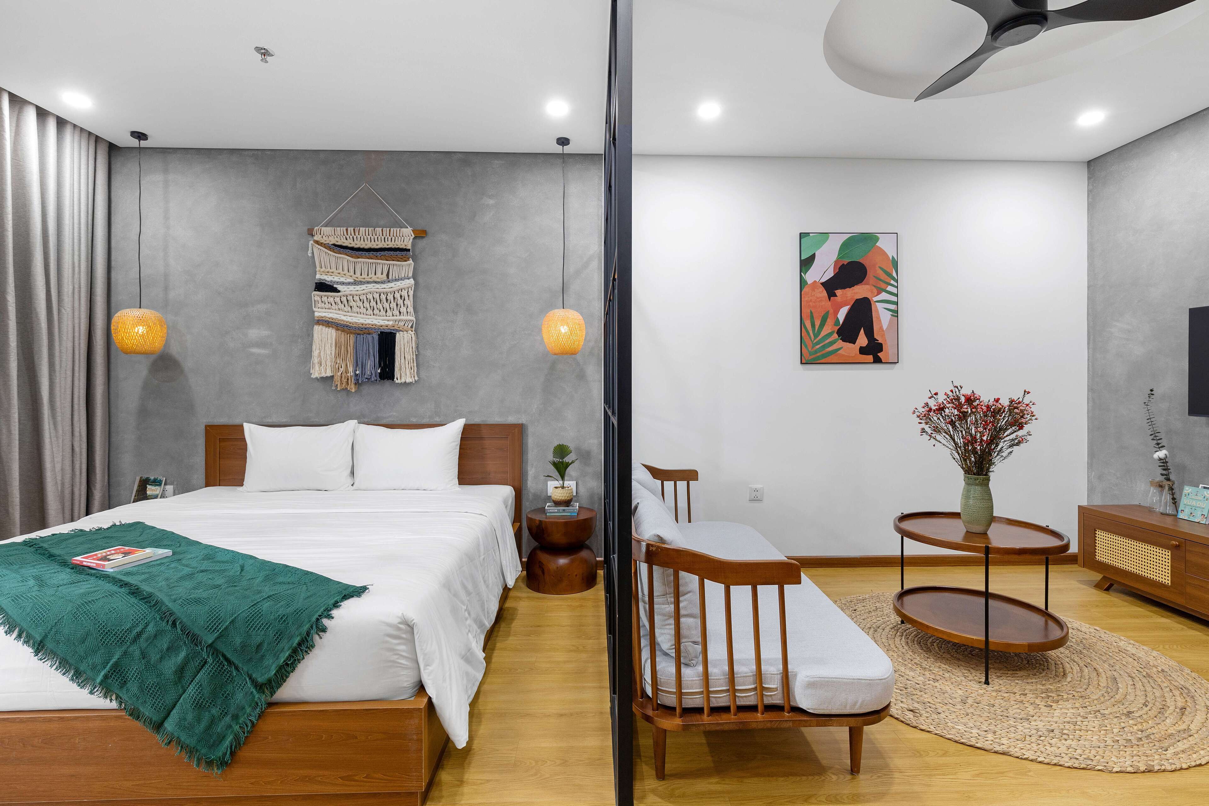 A modern bedroom with a large bed, bedside tables, a small seating area, and a decorative wall hanging.