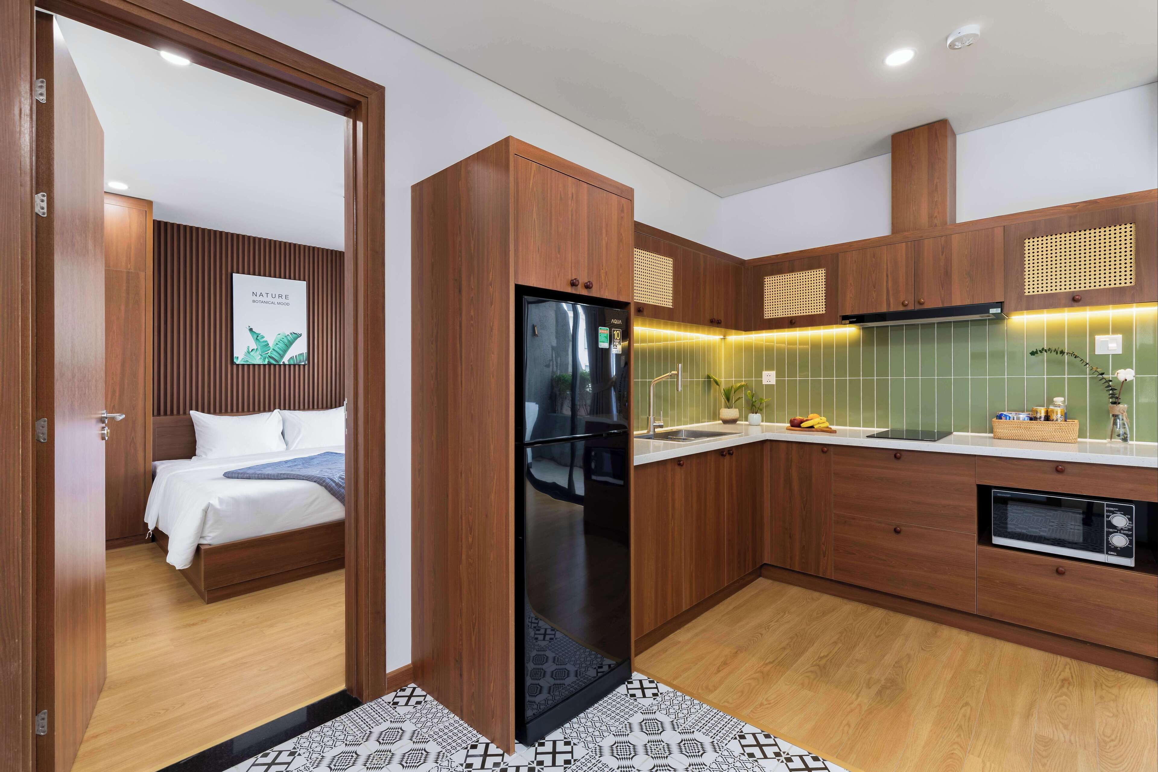 A modern kitchen with wooden cabinets, a black refrigerator, and a microwave.
