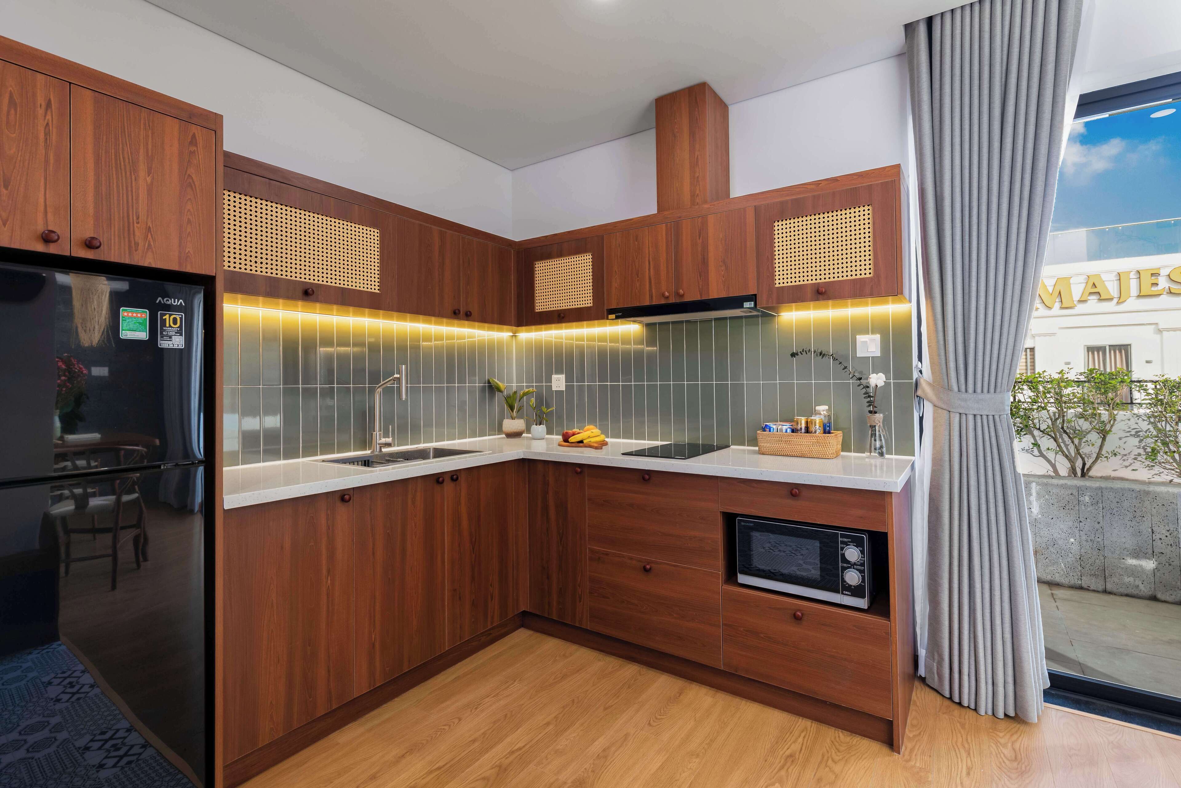A modern kitchen with wooden cabinets, a built-in microwave, and a large window with a view of the outside.