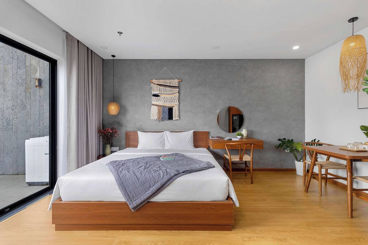 A modern hotel room with a large bed, a desk, and a dining area.