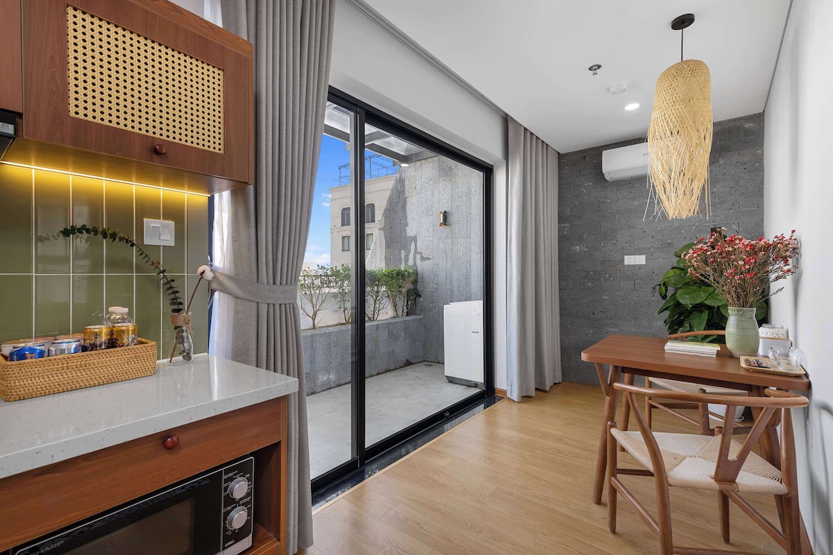 A modern kitchen with a built-in oven, a dining area with a wooden table and chairs, and a large sliding glass door leading to a balcony.