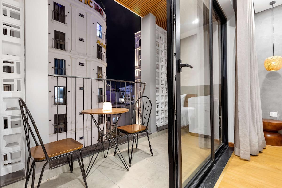 A balcony with a table and chairs, a glass door, and a view of a building with balconies.