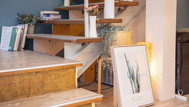 Una escalera de madera con barandilla blanca que lleva a un rellano con libros y objetos decorativos.