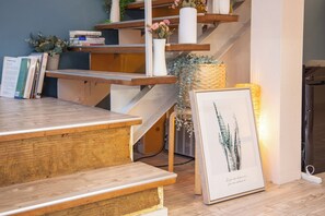 Una escalera de madera con barandilla blanca que lleva a un rellano con libros y objetos decorativos.