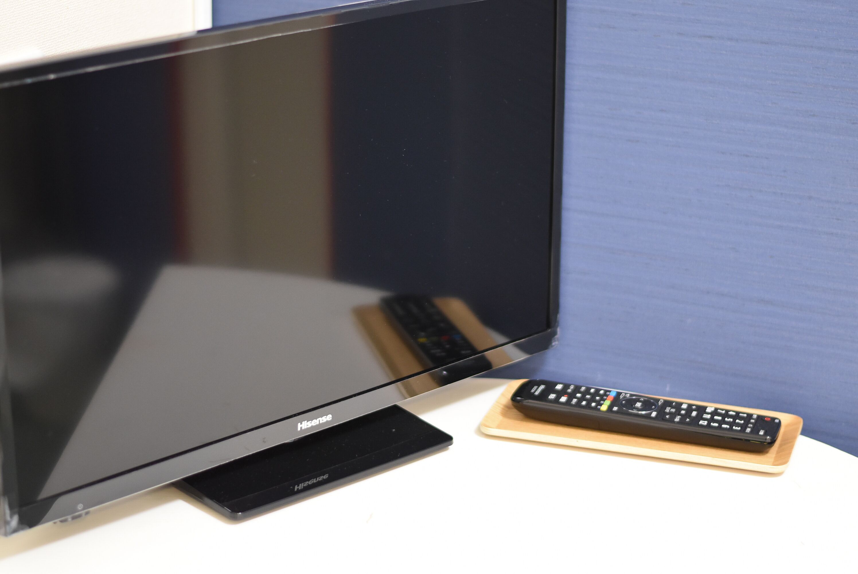 A flat-screen TV with a remote control on a stand.