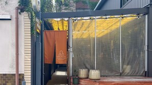 Una casa de huéspedes con un banco de madera, un dosel amarillo y un letrero que indica el camino hacia la casa de huéspedes.