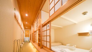 Una habitación tradicional japonesa con suelo de tatami, una cama baja de madera y puertas correderas shoji.