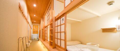 Una habitación tradicional japonesa con suelo de tatami, una cama baja de madera y puertas correderas shoji.