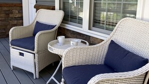 A porch with wicker furniture, including two chairs and a small table, and a window with blinds. - Charming home near PSU - built for memorable game days and family visits (State College)