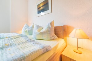 A neatly made bed with a patterned bedspread and pillows, a bedside lamp, and a framed picture on the wall.