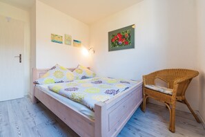 Un dormitorio con una cama de madera, una silla de mimbre y decoración en la pared.