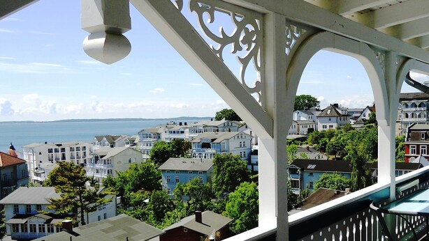 A coastal town with white buildings, a pier, and a view of the sea.