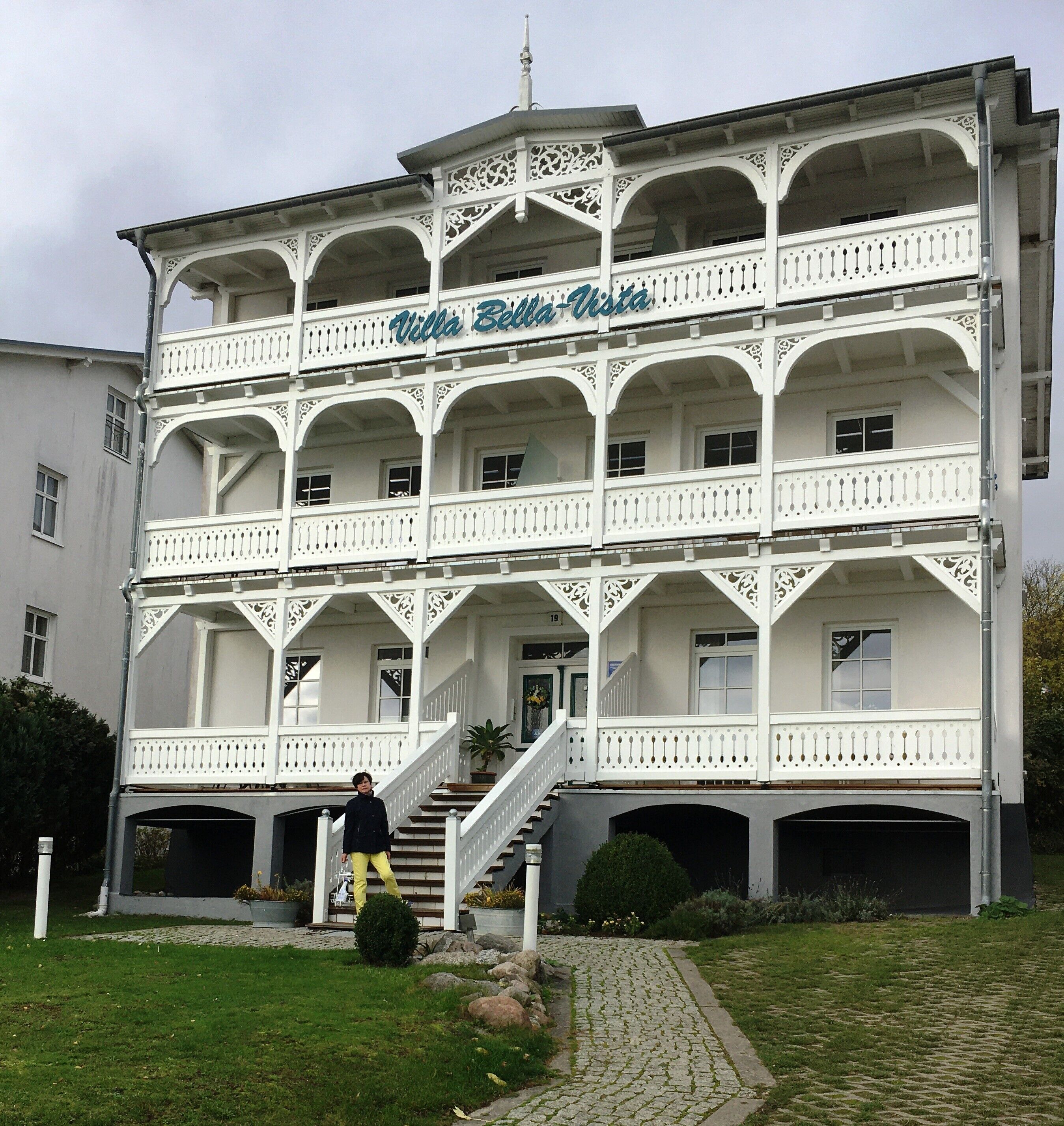 Un immeuble à plusieurs étages, doté de balcons et d’un escalier menant à l’entrée.