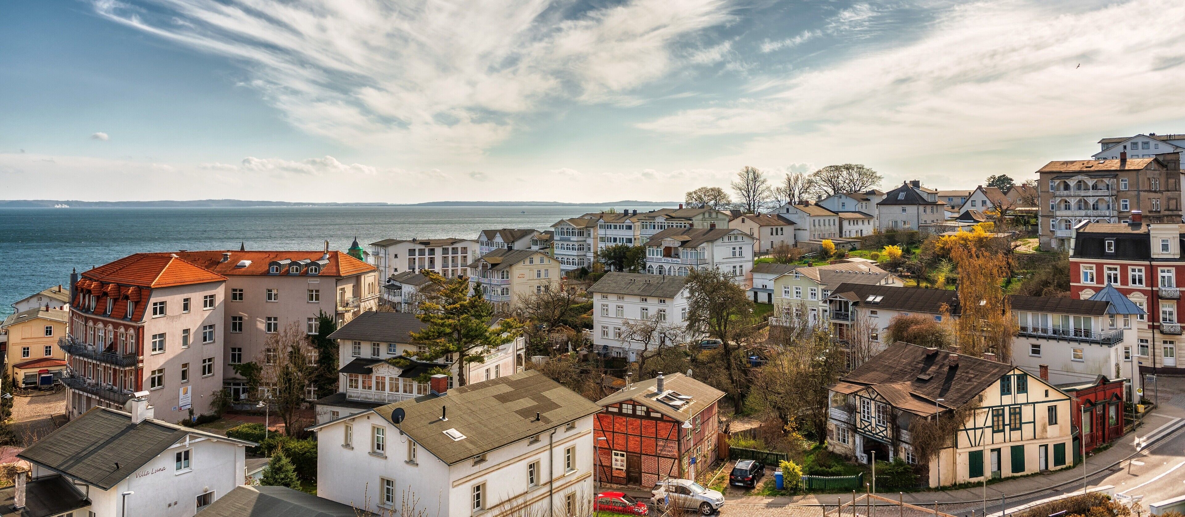 A coastal residential area with a variety of houses, some with balconies, and a view of the sea.