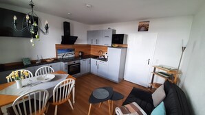 A modern kitchen with white cabinets, a black countertop, and a dining area with a wooden table and chairs.