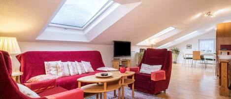 A modern living room with a red sofa, a wooden coffee table, and a TV.