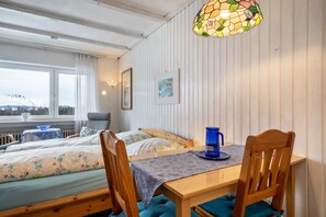 A room with two beds, a table with chairs, a stained glass window, and a view of the outdoors.